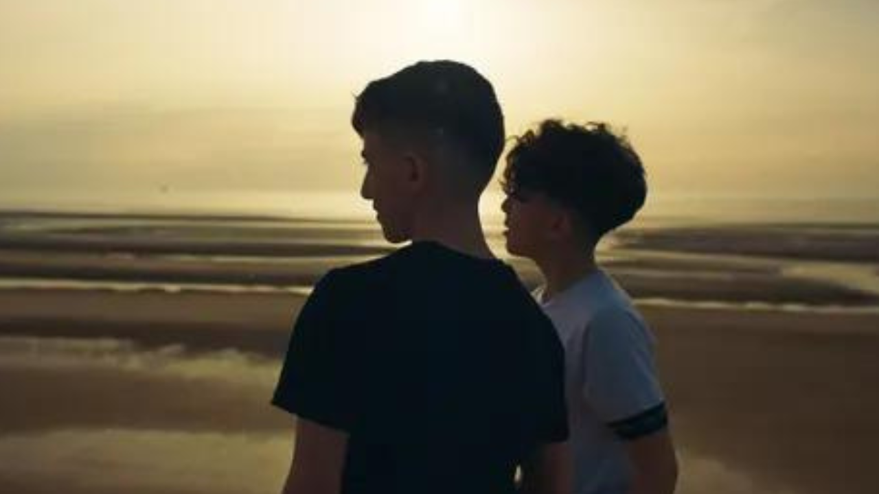 Two boys on a beach with a sunset.