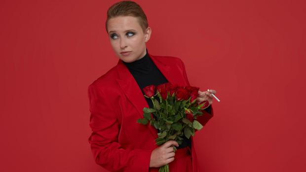 Hannah Maxwell - wearing a red jacket with black top holding a bunch of roses.